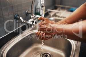 He takes his cleanliness seriously. an unrecognizable man washing his hands in the kitchen sink at home.