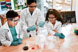 Science experiments encourage exploration. an adorable little boy and girl conducting a scientific experiment with their teacher at school.