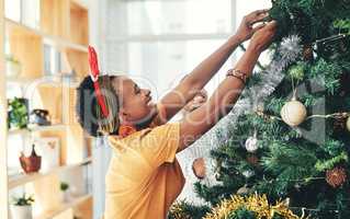 Just adding my own touch of magic to the decorations. an attractive young businesswoman decorating a Christmas tree in her office at work.