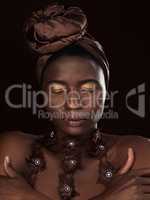 Wrapped to perfection. Studio shot of an attractive young woman posing in traditional African attire against a black background.