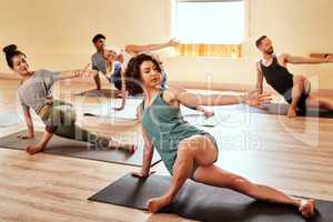 Twist your way to a flexible you. a group of young men and women practicing yoga in a fitness class.