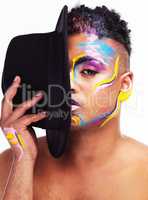 Show the world your best side. Portrait of a gender fluid young man wearing face paint and a hat posing against a white background.