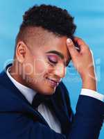 You feel good when you look good. a gender fluid young businessman posing against a blue background.