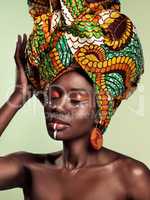 Do you know the history of the African head wrap. Studio shot of a beautiful young woman wearing a traditional African head wrap against a green background.