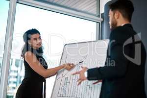 Staying informed with the data. an attractive young businesswoman standing and using a white board to present data to her male colleague.