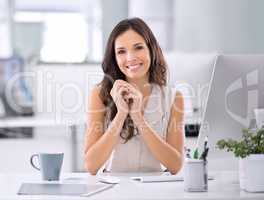 Happy and confident business woman sitting at her desk feeling proud of her career and job choice. Portrait of a female entrepreneur and leader feeling positive while working in a modern office