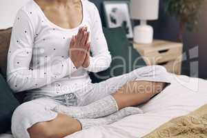 The longest journey is one inward. an unrecognizable woman meditating on her bed at home.