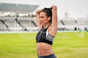 Stretching before warming up. an attractive young female athlete warming up on the track.