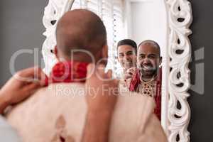 I think were ready to head for the altar now. a young best man helping the groom with getting dressed while standing in front of the mirror on the wedding day.