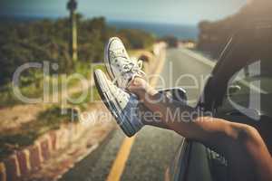 This is how I relax. an unrecognizable woman putting her feet up while on a road trip.