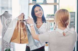 Happy staff helping a woman doing fashion shopping and spending on her favorite designer store. A stylish, excited and wealthy female buying clothes and enjoying good customer service