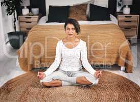 Mental health is just as important as physical health. an attractive young woman sitting and meditating by the foot of her bed in her bedroom.