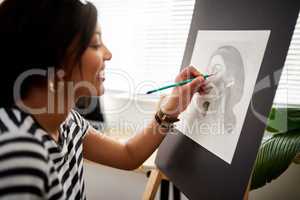 This picture is coming out exactly how I envisioned it. an attractive young artist drawing a portrait of a woman inside her studio.