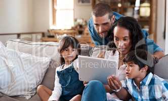 We found an educational app thats fun for all ages. a family of four watching something on a digital tablet.