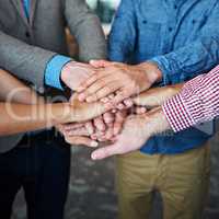 Teamwork, collaboration and support while putting hands together in an office for motivation and unity amongst colleagues. Group of businesspeople standing together in a huddle during team building