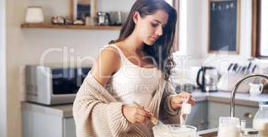 Bake your way to a relaxing day. an attractive young woman preparing breakfast at home.