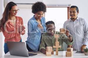 Making waves in the industry with a new business model. a group of young businesspeople having a meeting with building blocks in a modern office.