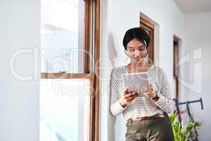 Wondering what task I should do first. an attractive young businesswoman standing and using a tablet in her office alone.