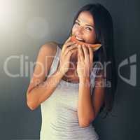 Healthy and slim woman eating fruit melon in summer sunlight with cool fitness lifestyle dark background. Face portrait of young girl biting into delicious, juicy and organic slice for a health diet