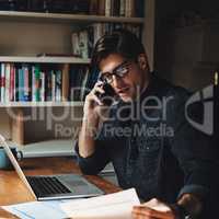 Time to call in few favors. a handsome young businessman making a phone call while working in his office at home.