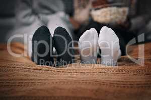 Friends are there to warm up your heart and feet. two young women wearing socks while lying on a bed together.