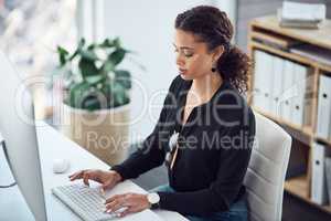 Leave it to her to get it all done. High angle shot of a young businesswoman working on a computer in an office.