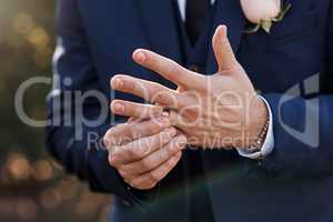The gold on his finger symbolises commitment. an unrecognizable bridegroom adjusting his ring on his wedding day.