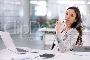 Confident businesswoman thinking about a corporate strategy to boost sales at her desk while holding a pen with her laptop open in an office. Successful professional female planning a campaign alone