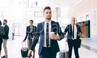 Bring on the next big work adventure. three businesspeople walking and pulling suitcases while in the office during the day.