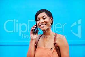 Calling my friends to come join in on the fun. Portrait of an attractive young woman making a phone call against a blue background.