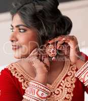 Because a bride has got to be elegant. a beautiful young bride putting on her earrings in preparation for her wedding.