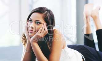 Cool, calm and collected. a young woman laying on the floor and daydreaming.