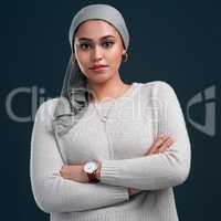 Learn to love the person that you are. an attractive young woman wearing a headscarf and standing with her arms folded against a black background.