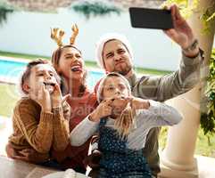 Lets share this special occasion with our loved ones. a family of four taking a selfie together on Christmas day.