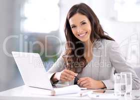 Happy, confident and ambitious business woman working on her laptop while sitting at her desk. Portrait of a beautiful female entrepreneur showing great leadership skills while working in an office