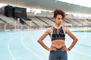 Im ready to train. an attractive young athlete standing akimbo after an outdoor track and field training session alone.