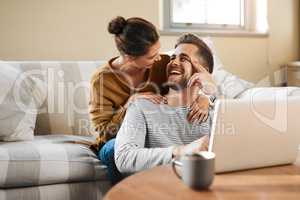 I just bought tickets to favorite show. a young couple using a laptop while relaxing at home.