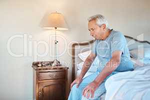 Thinking of how to spend my day. a senior man sitting alone on the edge of his bed and looking contemplative at home.