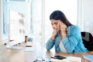 Stress is one of the main triggers of tension headaches. a young businesswoman looking stressed out while working in an office.