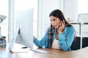 Please hold while I address the issue from my end. a young businesswoman wearing a headset while working on a computer in an office.