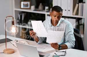 Making everything sure everything is complete and up to standard. a handsome young businessman going over some paperwork while working late in his office.