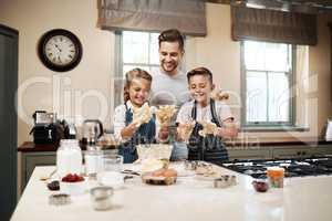 Its always fun when it involves getting your hands dirty. a man and his two children baking in the kitchen at home.