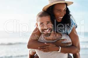 Love is such a blissful feeling. Portrait of a young man piggybacking his girlfriend at the beach.