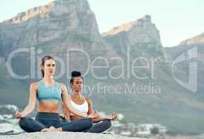 Yoga is a way to call for calm. two sporty young woman practicing yoga together outdoors.