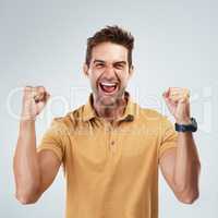 Looks like Im in the lead. Portrait of a cheerful young man punching the air in excitement while standing against a grey background.