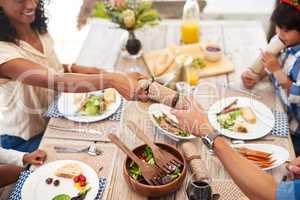 Their presence is the biggest gift of all. a young woman passing a gift over to her husband while having a meal with family outdoors.