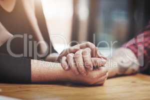 Support, compassion and trust while holding hands and sitting together at a table. Closeup of a loving, caring and affectionate couple comforting and helping each other through a difficult time