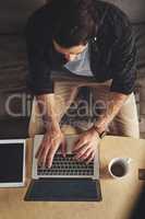 The internet holds a world of entertainment. High angle shot of a handsome young man using his laptop while relaxing on a couch at home.