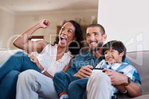 Mom is our biggest fan. a man playing video games while relaxing at home with his wife and son.