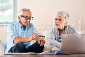 Not every transaction needs a trip to the bank. a senior couple using a credit card while going through paperwork at home.